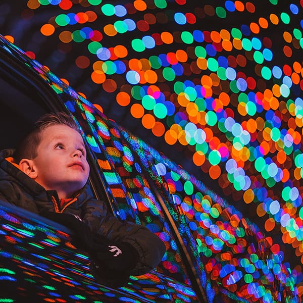 Boy gazing out of the window of a vehicle at Christmas lights