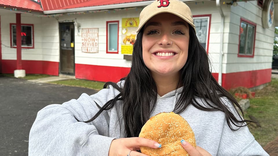 Smiling girl eating a burger baron hamburger in Leduc