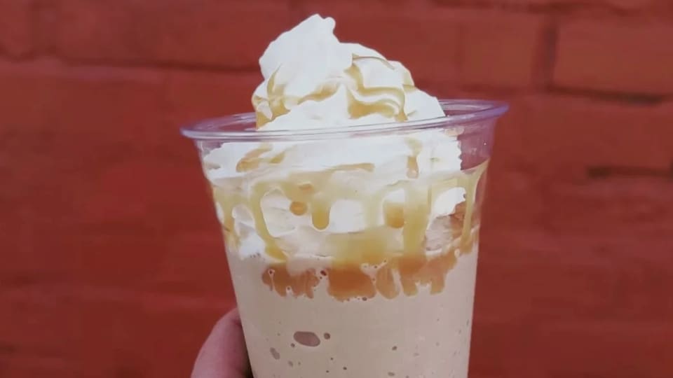 Frozen coffee drink with whipped cream against a brick wall