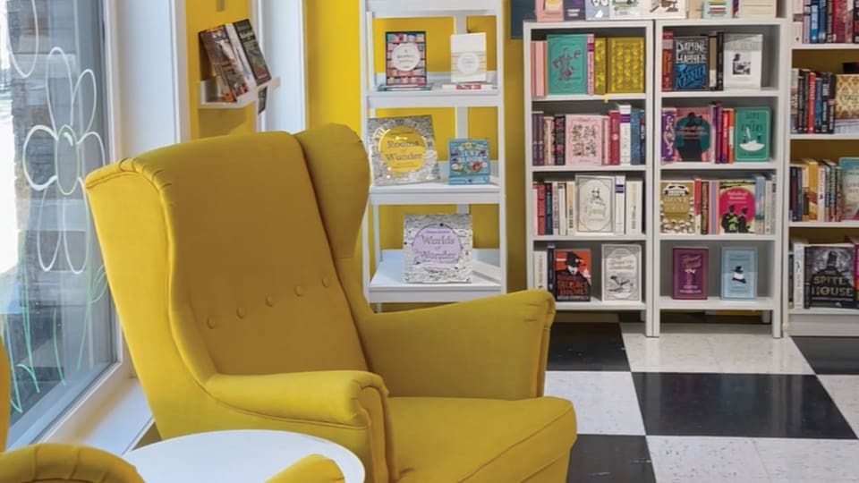 Bright, yellow chairs in front of a window in the bookstore with black and white checkered floors