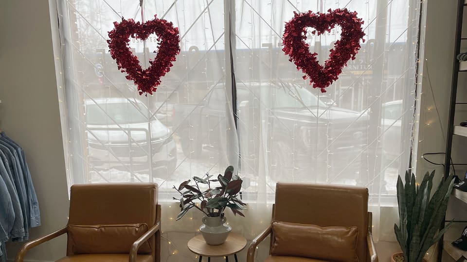 Cute Valentine's Day hearts in the window of the store, complimented with two comfy brown leather chairs.